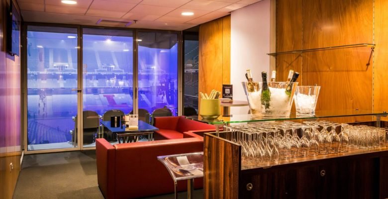 Loge VIP aménagée avec bar comptoir bois et fauteuils cuir - Decathlon Arena Stade Pierre Mauroy Lille